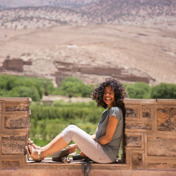 Isi sitting on a wall with a bleak landscape in the background