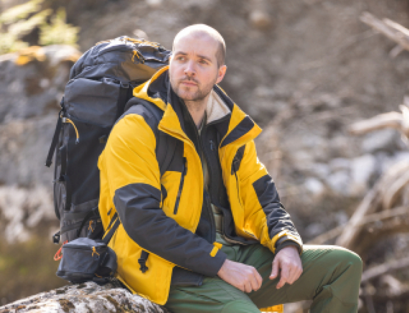 Chris sitting on a tree stump with a hiking pack